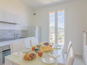 A modern kitchen with a dining area, a view of the city, and a balcony. - La Casa di Giulia (Borghetto Santo Spirito)