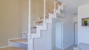 Eine moderne Treppe mit minimalistischem Design, ein Wohnbereich mit einer Couch und ein Topf mit Pflanze an der Wand.
