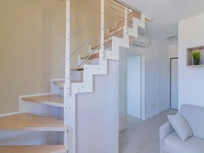 A modern staircase with a minimalist design, a living area with a sofa, and a potted plant on the wall. - La Casa di Giulia (Borghetto Santo Spirito)