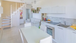 Eine moderne Küche mit weißen Schränken, einem eingebauten Backofen und einem Essbereich mit weißem Tisch und Stühlen.