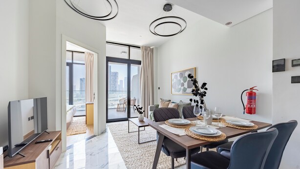 A modern living room with a dining area, a television, and a fire extinguisher. - Bloomfields 1BR Al Maryah Vista  (Abu Dhabi)