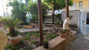 Um pátio com plantas em vasos, uma parede de pedra e um portão branco.