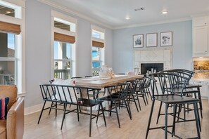 A dining area with a large wooden table, black chairs, and a fireplace. - The Big Fish on Redfish - amazing views, hot tub, outdoor bar, and more!! (Crystal Beach)