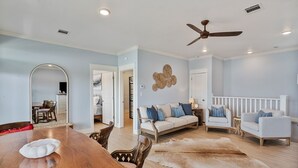 A spacious living room with a wooden dining table, a sofa set, a ceiling fan, and a large mirror. - The Big Fish on Redfish - amazing views, hot tub, outdoor bar, and more!! (Crystal Beach)