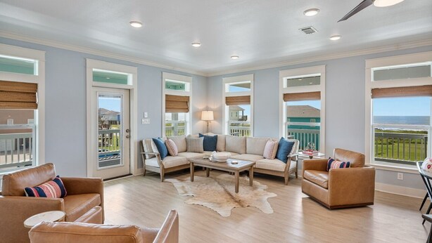 A spacious living room with a large sectional sofa, a coffee table, and a view of the ocean through large windows. - The Big Fish on Redfish - amazing views, hot tub, outdoor bar, and more!! (Crystal Beach)