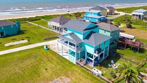 A coastal property with multiple buildings, a beach view, and a well-maintained lawn. - The Big Fish on Redfish - amazing views, hot tub, outdoor bar, and more!! (Crystal Beach)