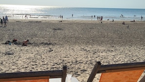 A beach with two wooden chairs and a table, a clear sky, and the ocean in the background. - Charming studio apartment, located in a quiet residential complex near the beach in Le Touquet (Paris)