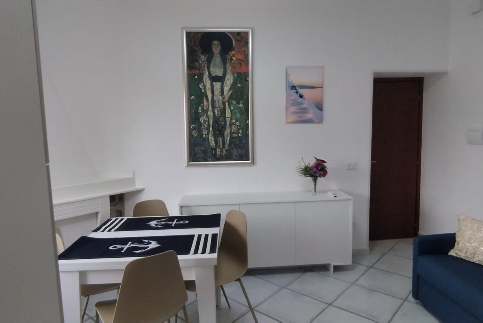 A dining area with a table, chairs, a white cabinet, and a painting on the wall.