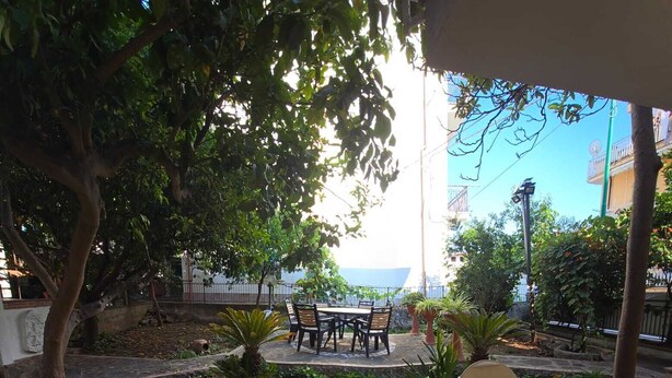 An outdoor seating area with tables and chairs, surrounded by potted plants and a stone wall. - Vacation Apartments Along the Agropoli Seafront (Agropoli)