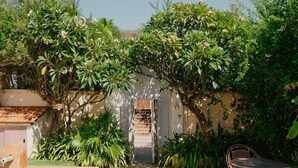 Ein Pool, ein Garten mit verschiedenen Pflanzen, eine Treppe, die zu einer Tür führt, und ein Tisch mit Stühlen.