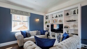 A living room with a sofa set, a television, and a bookshelf. - Host Stay - Welton Mews (Whitby)
