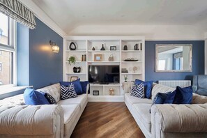 A living room with two sofas, a TV, and a bookshelf. - Host Stay - Welton Mews (Whitby)