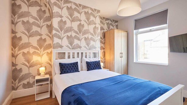 Una camera da letto con un letto, un comodino, un armadio e una finestra.