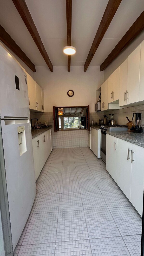 A kitchen with white cabinets, a tiled floor, and wooden beams on the ceiling.