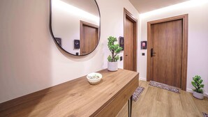 Ein Flur mit einem hölzernen Empfangstresen, einem großen Spiegel, einem Blumentopf und zwei Holztüren.