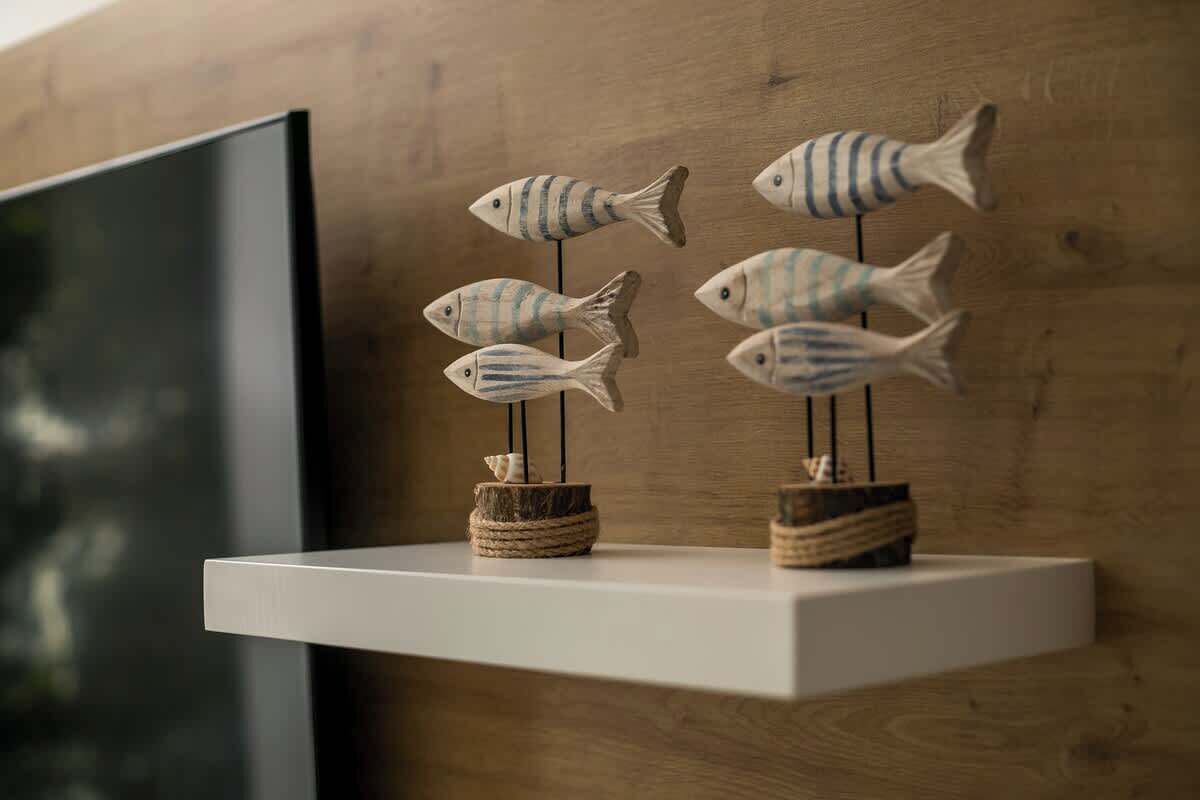 A wooden wall with a white shelf holding fish-shaped decorations.