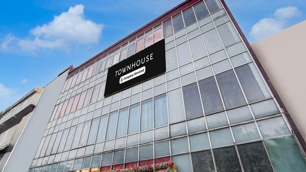 A modern building with a large glass facade and a sign that reads 'TOWNHOUSE Company Serviced.' - Deluxe Patparganj Near Max Hospital (New Delhi)