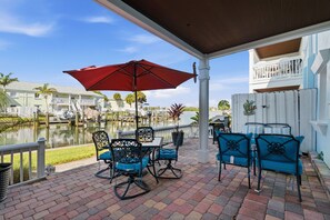 A covered patio with outdoor seating, a view of a marina, and a pool. - Waterside at Coquina Key island Living (St. Petersburg)