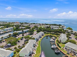 A marina with boats docked, surrounded by residential buildings with balconies, and a clear view of the ocean. - Waterside at Coquina Key island Living (St. Petersburg)