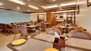Comedor de hotel con varias mesas y sillas, con vajilla y servicios.