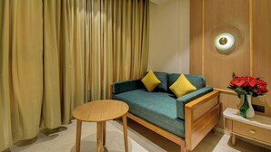 Una habitación con sofá, una mesita redonda, un armario de madera y una cortina.