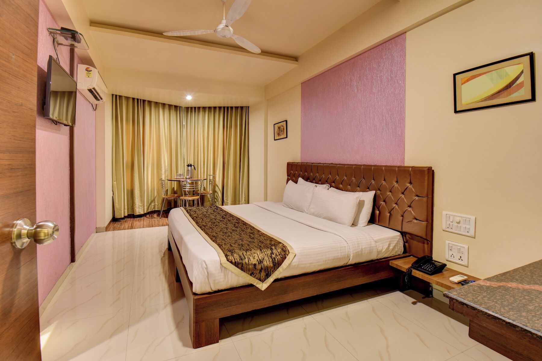 A hotel room with a bed, bedside table, and a ceiling fan.