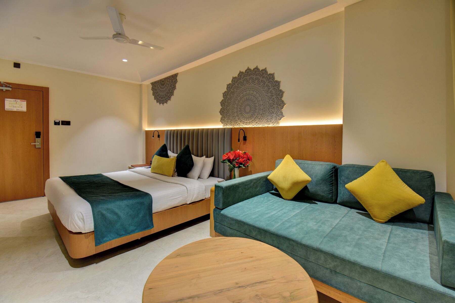 Una habitación de hotel con cama, sofá, una mesa redonda de madera y decoración en la pared.