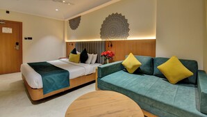 Una habitación de hotel con cama, sofá, una mesa redonda de madera y decoración en la pared.