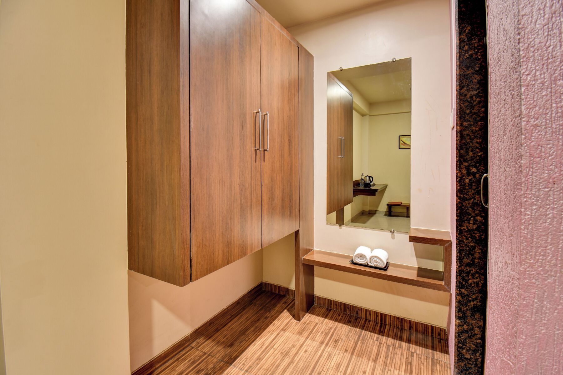 A bathroom with a wooden wardrobe, a mirror, and a towel rack.