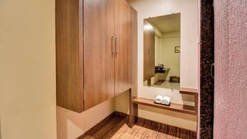 A bathroom with a wooden wardrobe, a mirror, and a towel rack.