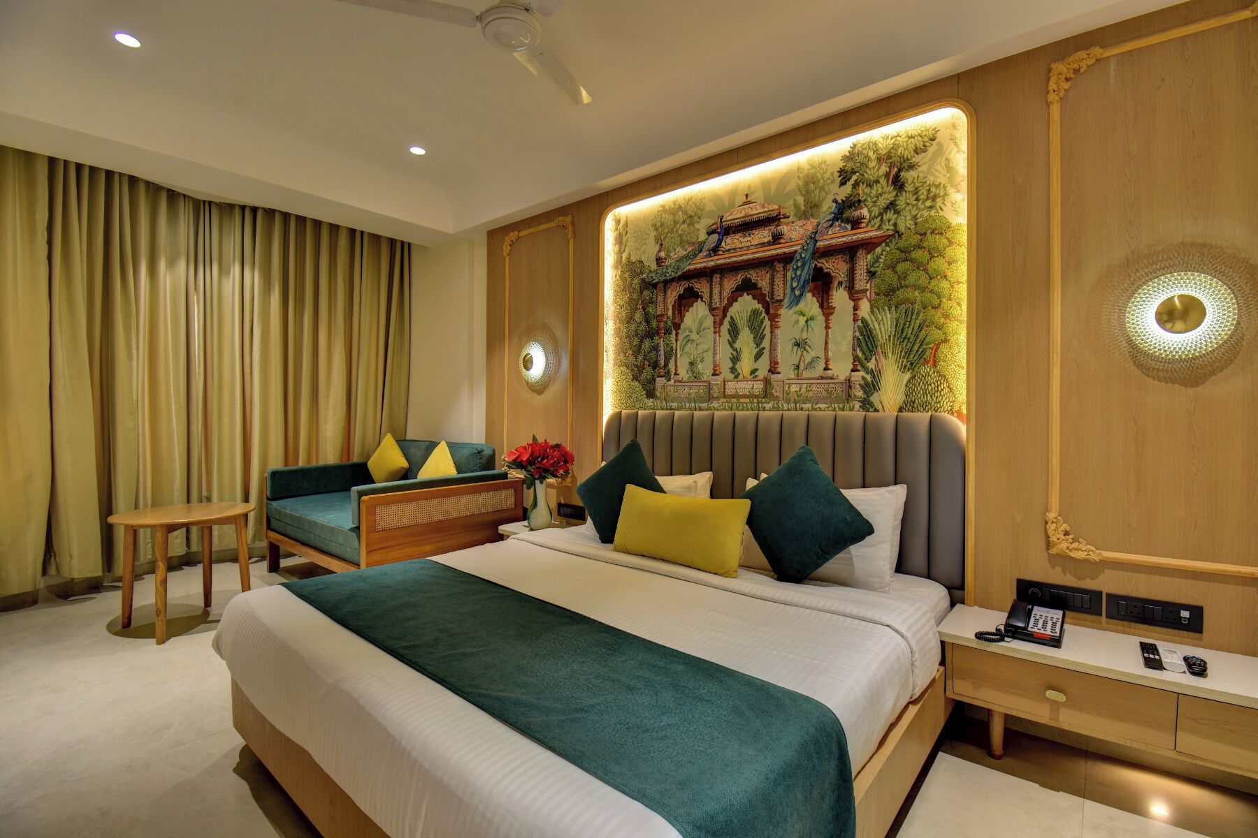 Une chambre d’hôtel dotée d’un grand lit, d’un coin salon avec un canapé et un fauteuil, d’un bureau avec un téléphone et d’une fresque murale décorative.