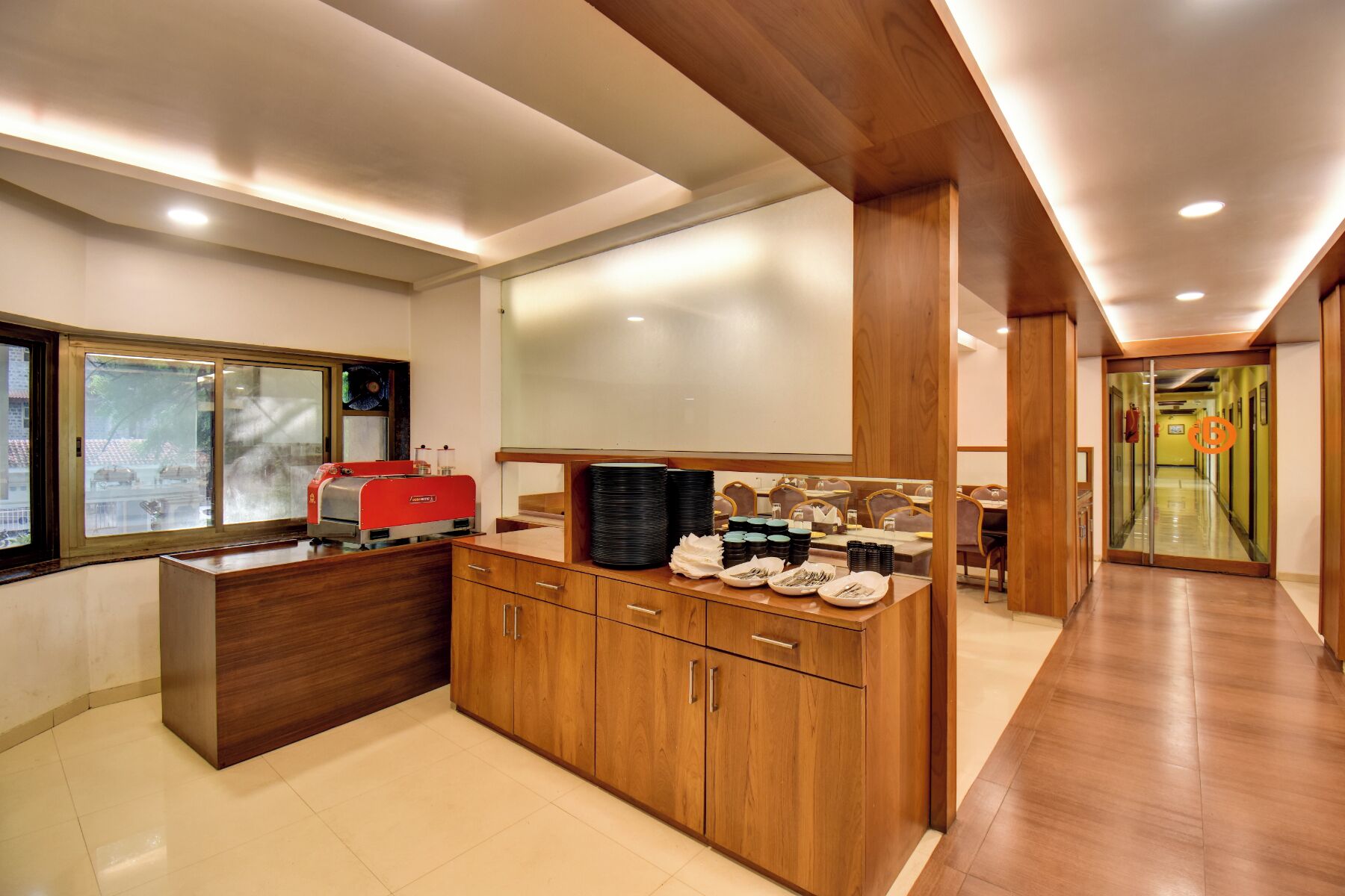 Uma cozinha moderna com máquina de café integrada, armários de madeira e um espaço de refeições com mesas e cadeiras.
