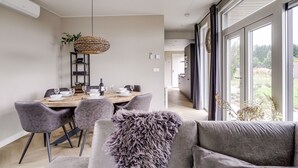 A modern dining area with a wooden table set for four, surrounded by grey upholstered chairs.