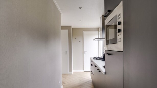 A modern kitchen with a built-in oven, microwave, and a stainless steel range hood.