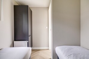 A room with two beds, a radiator, and a wardrobe.