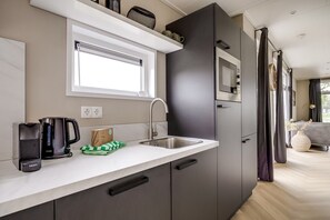 A modern kitchen with a built-in microwave, a kettle, and a coffee maker. - Cube XL 77 | 6 persoons chalet in Zennewijnen (Zennewijnen)