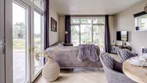 A modern bedroom with a large bed, a seating area, and a television.