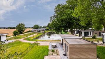 A residential area with modern houses, a small pond, and a grassy field.