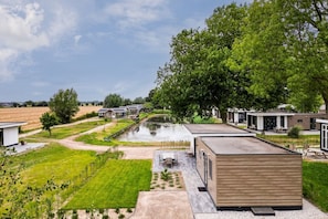 A residential area with modern houses, a small pond, and a grassy field.