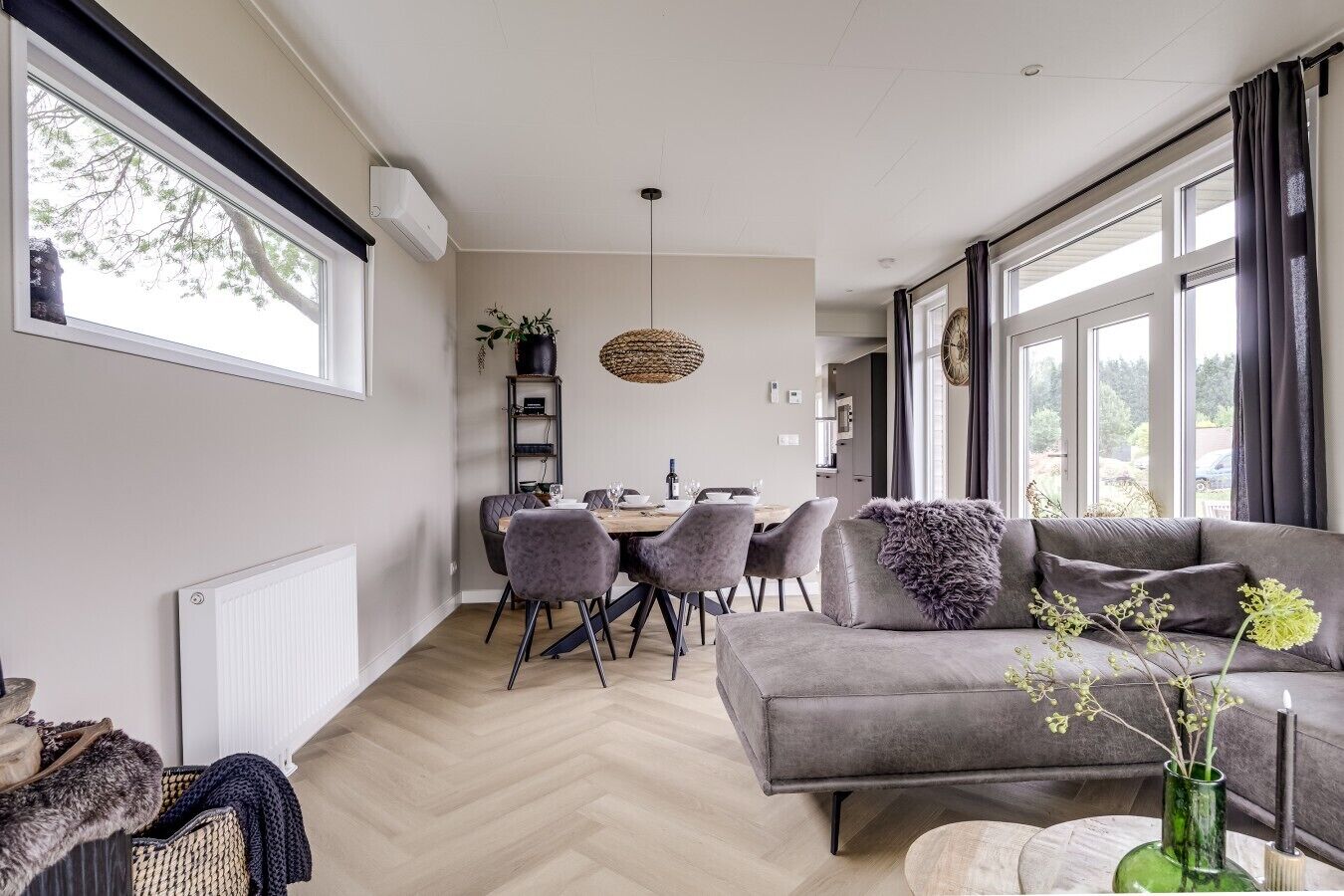 Una sala moderna con un sofá gris, una mesa de comedor y sillas.
