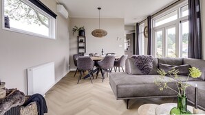 Una sala moderna con un sofá gris, una mesa de comedor y sillas.
