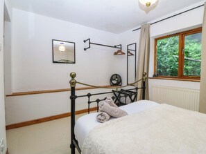 A bedroom with a bed, a radiator, a window with a view of greenery, a wall-mounted fan, and a picture. - Waterfall Retreat (Blaenau Ffestiniog)