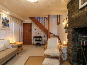 A cozy living room with a stone fireplace, a wooden staircase, a map on the wall, and a sofa. - Waterfall Retreat (Blaenau Ffestiniog)