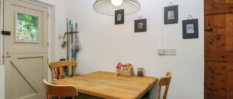 A dining area with a wooden table, chairs, a hanging light fixture, and a door with a window.