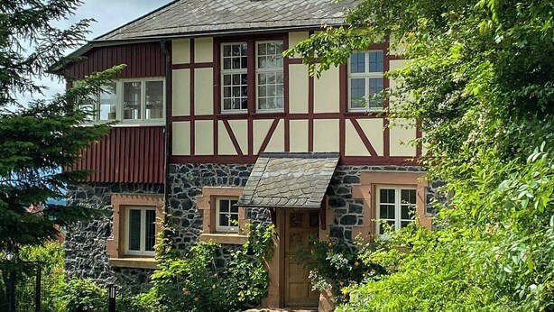 Una casa tradizionale a graticcio con facciata in pietra, un camino e un vialetto in pietra che conduce all'ingresso.