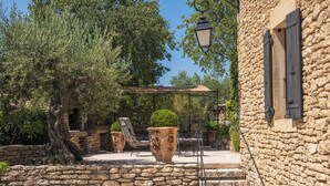 Un edificio in pietra con un’area esterna rustica, comprensiva di un pergolato e mobili da giardino.