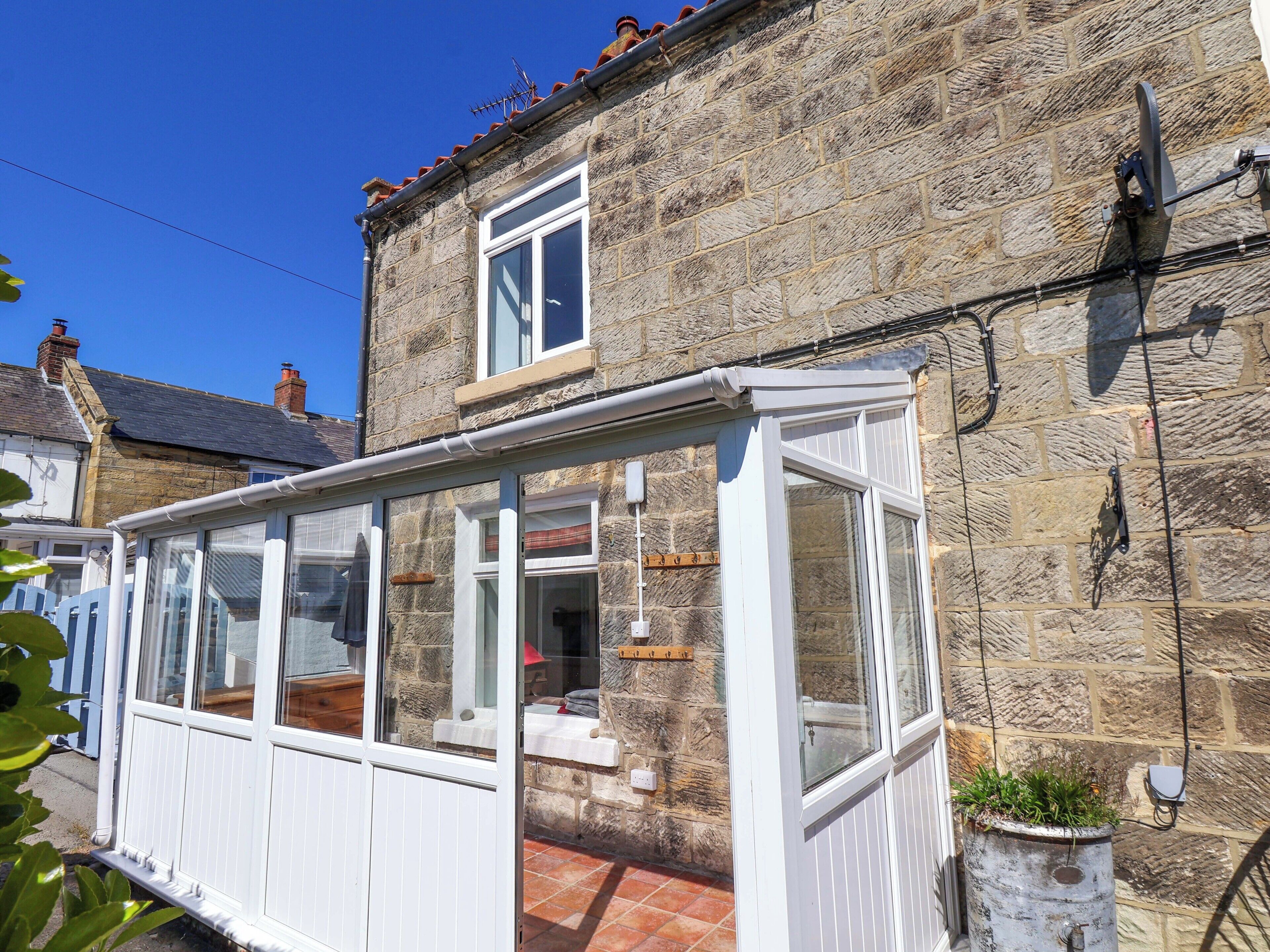 A stone building with a conservatory, a window, and a satellite dish.