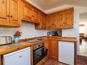 Une cuisine avec des meubles de rangement en bois, une cuisinière, un lave-vaisselle et un four à micro-ondes.