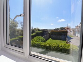 Una ventana con vista a una zona residencial, que incluye un seto, una valla y casas.