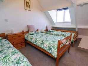 Une chambre à coucher avec deux lits en bois, une commode en bois, une petite table et une fenêtre donnant sur un beau paysage.
